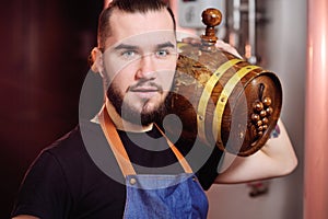 Attractive winemaker holds a wooden barrel of wine