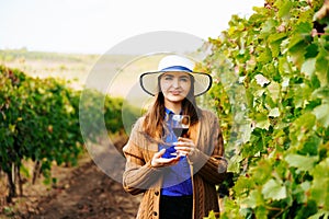 Attractive winemaker woman holding a glass of red wine in her hand and looking at the camera