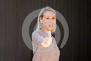 Attractive winking woman sticking out her tongue giving a thumbs up gesture