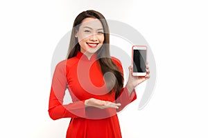 Attractive woman in ao dai dress showing screen mobile phone, isolated on white background