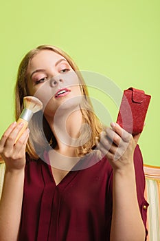 Attractive woman applying make up with brush