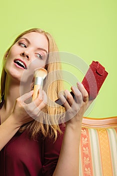 Attractive woman applying make up with brush.