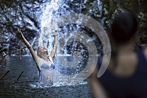 An attractive woman bathing near the waterfall.