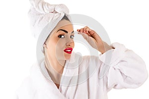 Attractive woman in bathrobe plucks eyebrows