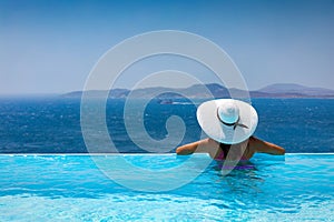 Attractive woman enjoys the view from the pool to the Mediterranean sea