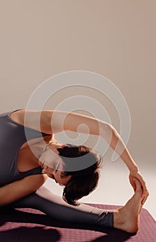 Attractive woman bending body close up. Athletic woman stretches her body on a mat in the studio