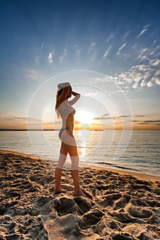 Attractive woman in bikini walking on sand on lonely beach