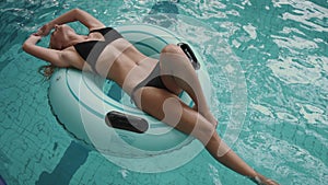 attractive woman in black bikini swimming on the inflatable rubber ring in the pool. 4k.