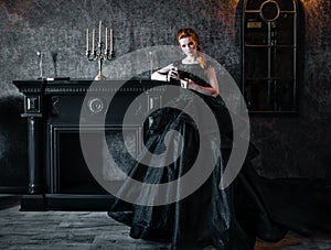 Attractive woman in black dress in medieval interior