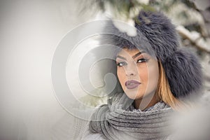 Attractive woman with black fur cap and gray shawl enjoying the winter. Frontal view of fashionable brunette girl with makeup