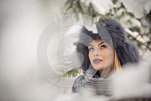 Attractive woman with black fur cap and gray shawl enjoying the winter. Frontal view of fashionable brunette girl with makeup
