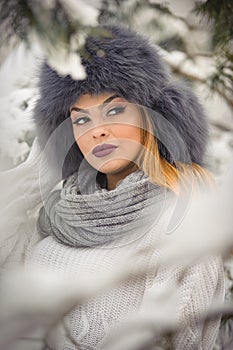 Attractive woman with black fur cap and gray shawl enjoying the winter. Frontal view of fashionable brunette girl with makeup