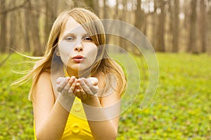 Attractive woman blowing kiss in spring nature