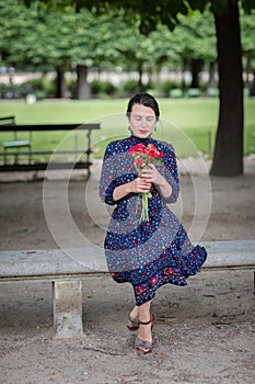 Attractive woman in a blue dress sitting in the park