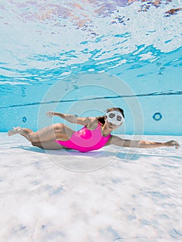 Attractive woman in bright swimwear swimming underwater in pool