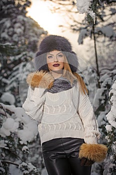 Attractive woman with brown fur cap and jacket enjoying the winter. Side view of fashionable blonde girl posing