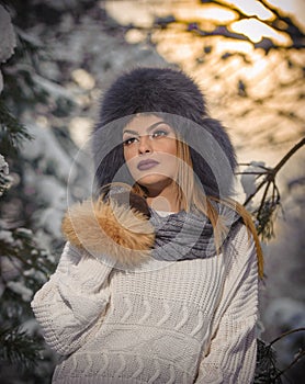 Attractive woman with brown fur cap and jacket enjoying the winter. Side view of fashionable blonde girl posing