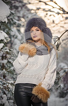 Attractive woman with brown fur cap and jacket enjoying the winter. Side view of fashionable blonde girl posing
