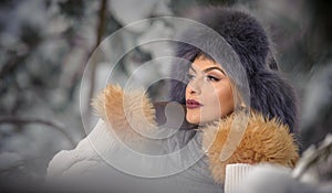 Attractive woman with brown fur cap and jacket enjoying the winter. Side view of fashionable blonde girl posing