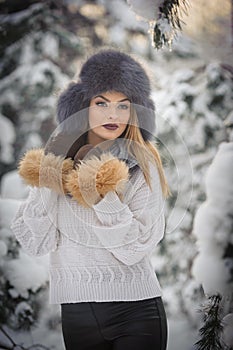 Attractive woman with brown fur cap and jacket enjoying the winter. Side view of fashionable blonde girl posing