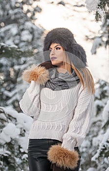 Attractive woman with brown fur cap and jacket enjoying the winter. Side view of fashionable blonde girl posing