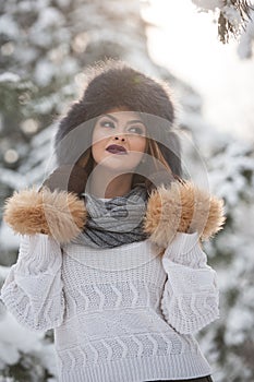 Attractive woman with brown fur cap and jacket enjoying the winter. Side view of fashionable blonde girl posing