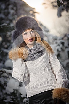 Attractive woman with brown fur cap and jacket enjoying the winter. Side view of fashionable blonde girl posing