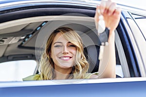 An attractive woman in a car gets the car keys. Rent or purchase of auto.