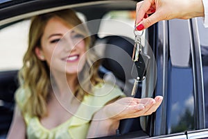 An attractive woman in a car gets the car keys. Rent or purchase of auto.