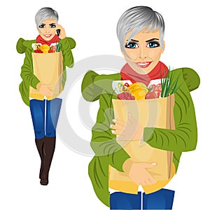 Attractive woman carrying grocery paper bag full of healthy food while talking on the mobile phone