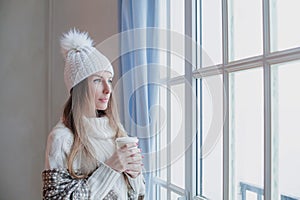 Attractive woman in casual winter clothes with hot drink indoor