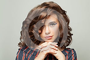 Attractive woman with clear skin and dark curly bob hairdo on white