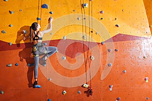 Attractive woman climbing up the wall in gym