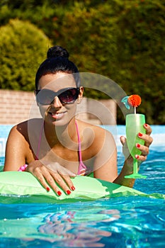 Attractive woman with cocktail in swimming pool