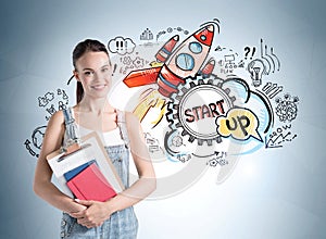 Attractive woman in denim holding a clipboard, notebooks and dreaming about start up and how to succeed on it. Concept of success