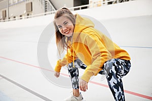 Attractive woman doing warm up muscles before training and smile. Morning fitness and sport as lifestyle. Athletic outdoor