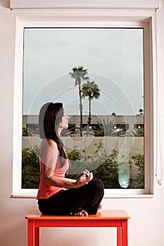 Attractive woman doing yoga by window