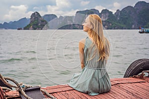 Attractive woman in a dress is traveling by boat in Halong Bay. Vietnam. Travel to Asia, happiness emotion, summer