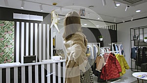 Attractive woman dressed in a fur coat is taking a selfie at clothing store, tracking shot, 360 degree