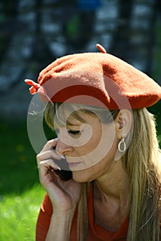 Attractive woman, dressed in orange with hat, talking on the phone