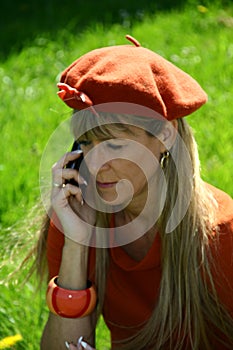 Attractive woman, dressed in orange with hat, talking on the phone