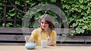 Attractive woman is drinking tea in her yard. young brunette enjoying a cup of tea outdoors