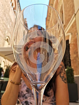 Attractive woman drinking white wine outdoors in a bar on the street, summer, italy