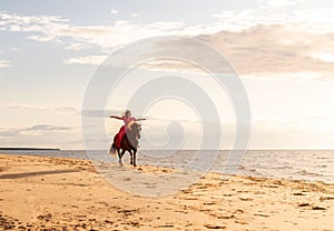 Attractive woman enjoying a leisurely ride on the back of a white horse along a sandy beach