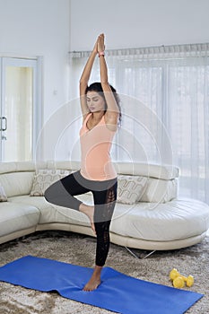 Attractive woman exercising yoga with tree pose