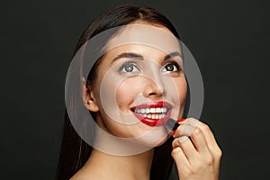 Attractive woman face with red lips and lipstick close up on black background