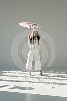 attractive woman in fashionable winter sweater and scarf standing with paper umbrella