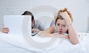 Attractive woman feeling upset unsatisfied and frustrated in bed with his husband while the man work on computer laptop ignoring h