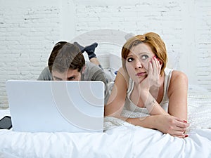 attractive woman feeling upset unsatisfied and frustrated in bed with his husband while the man work on computer laptop ignoring h