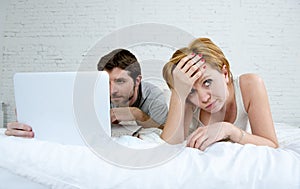 attractive woman feeling upset unsatisfied and frustrated in bed with his husband while the man work on computer laptop ignoring h